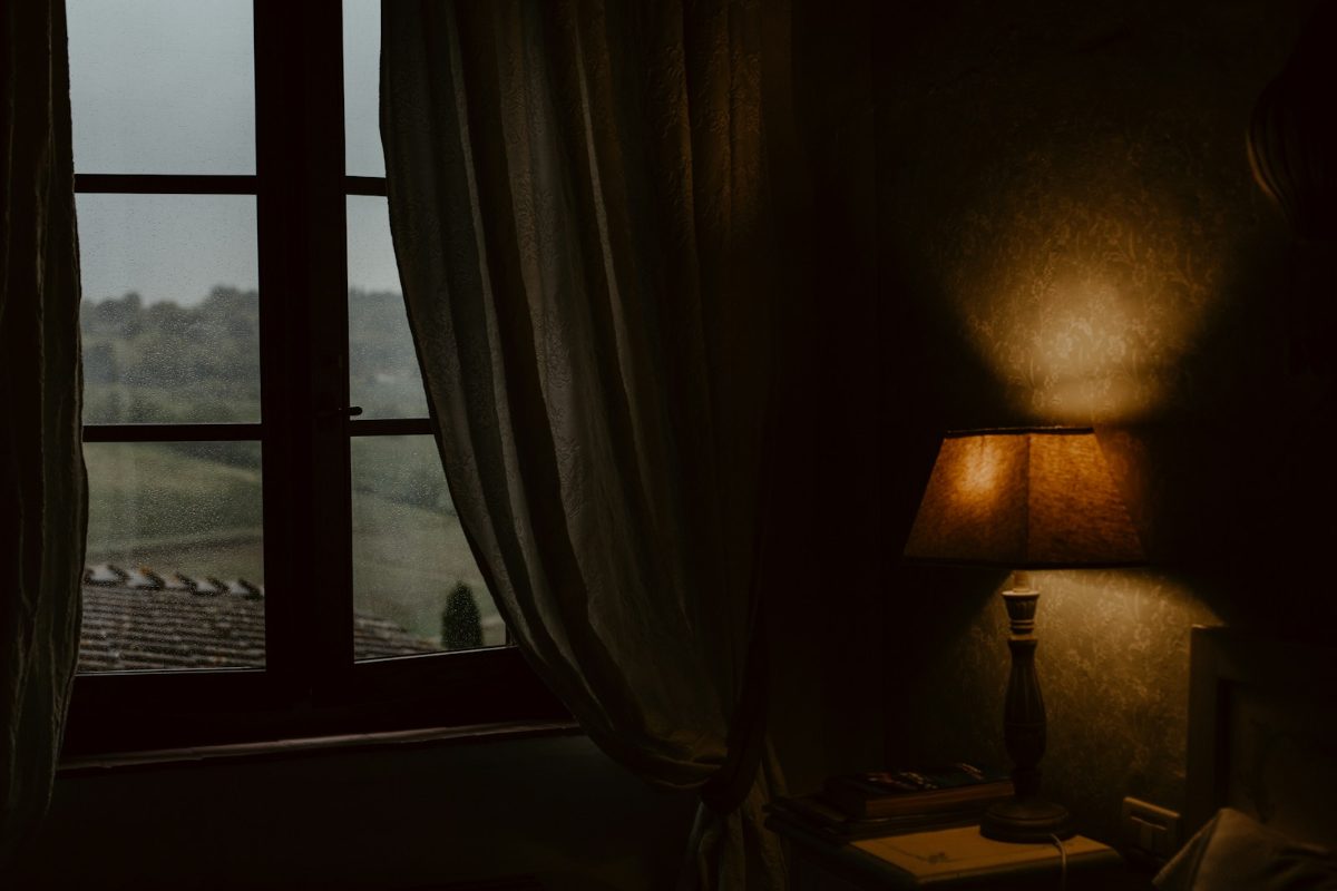 Warm leuchtende Stehlampe neben einem Fenster im abendlichen Zimmer
