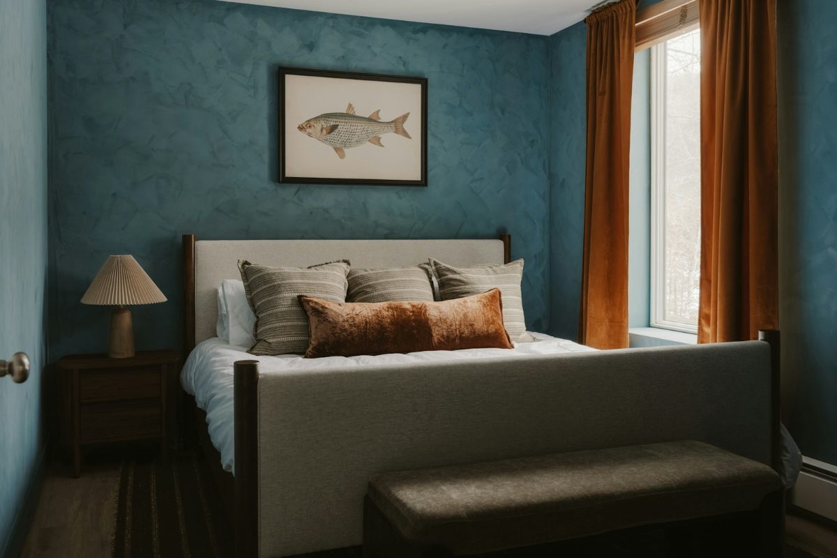 Schlafraum mit dunkelblauer Wand, hellem Bett und warmen Holztoenen