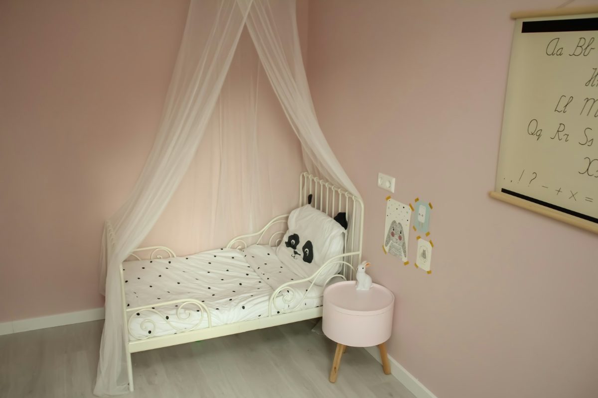 Kleines Kinderbett mit Betthimmel in einer ruhigen Zimmerecke
