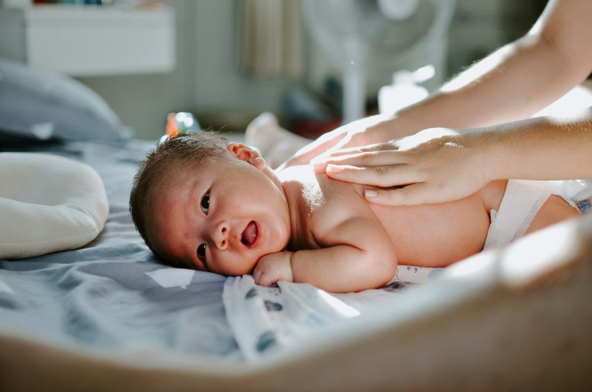 Baby liegt entspannt auf einer weichen Unterlage und wird versorgt