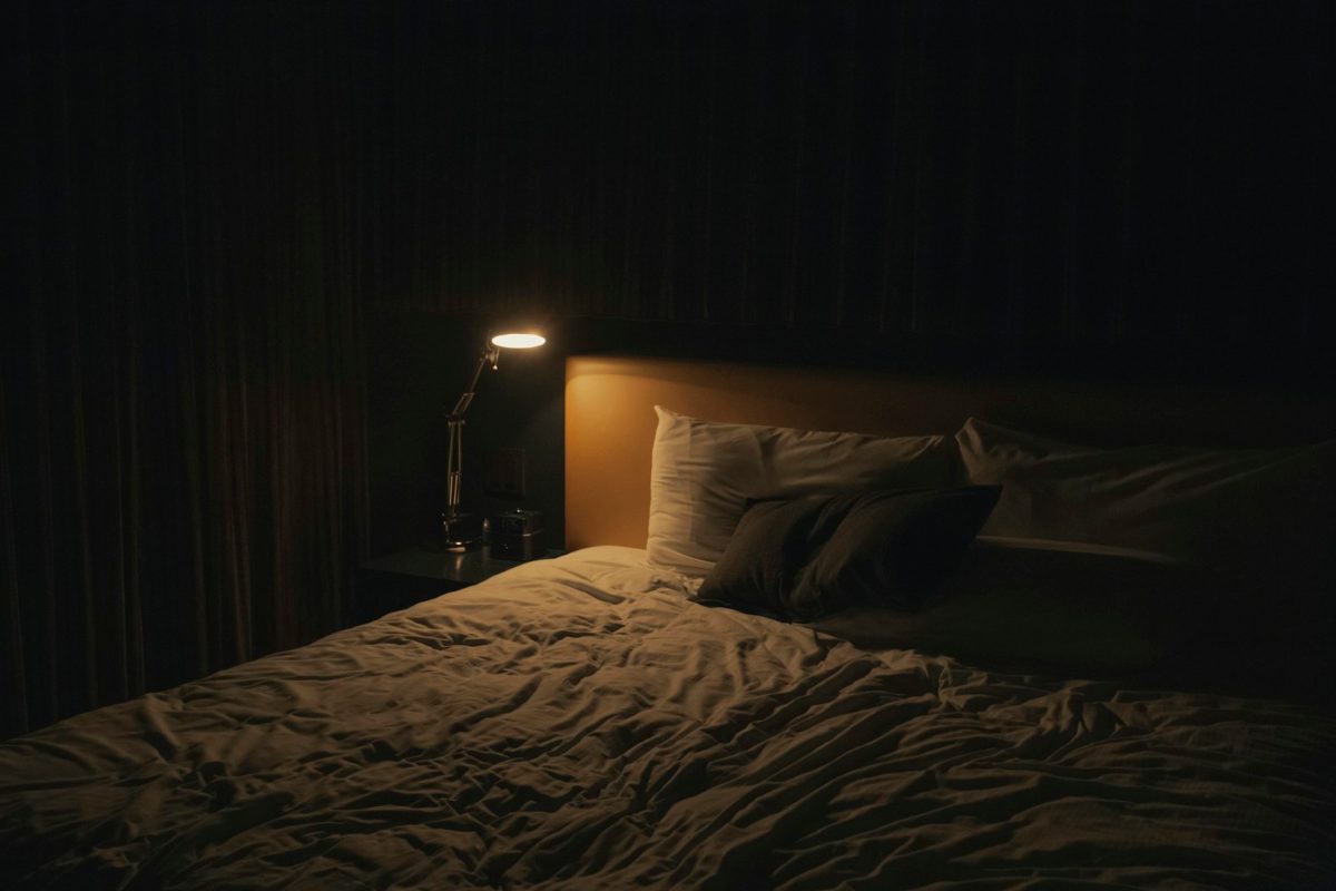 Abgedunkelter Schlafraum mit warmem Licht einer kleinen Nachttischlampe