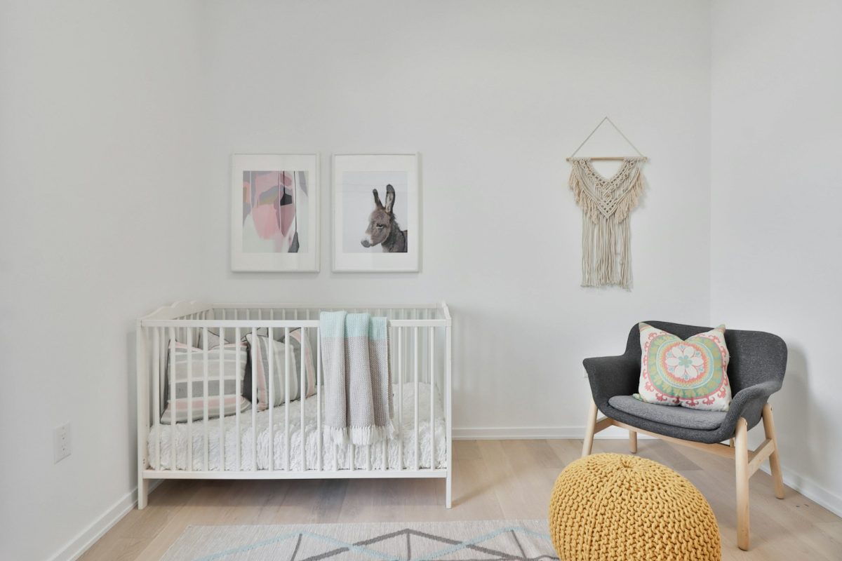 Helles Boho-Babyzimmer mit Gitterbett, Makramee-Wandbehang und Strickpouf
